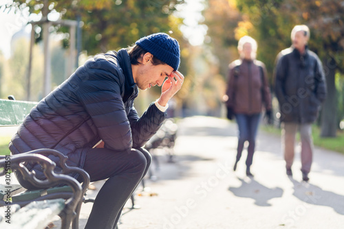 Worried young man on a bench during autumn day