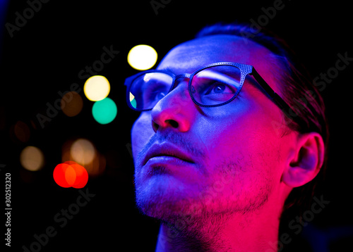 Modern red and blue light portrait of a young man in glasses