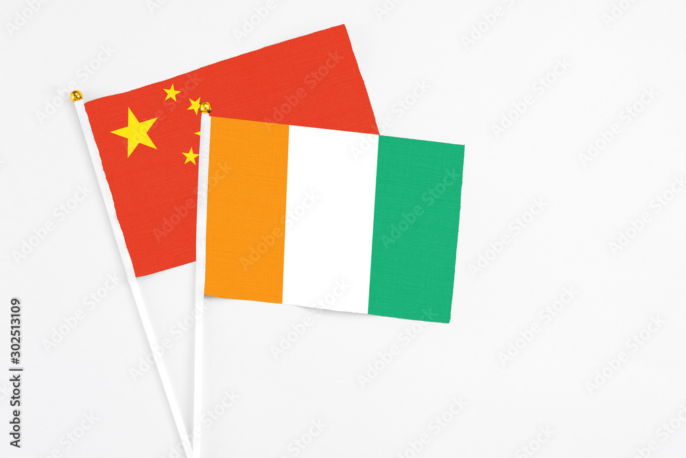 Cote D'Ivoire and China stick flags on white background. High quality fabric, miniature national flag. Peaceful global concept.White floor for copy space. Cote D'Ivoire and China stick flags on white background. High quality fabric, miniature national flag. Peaceful global concept.White floor for copy space.