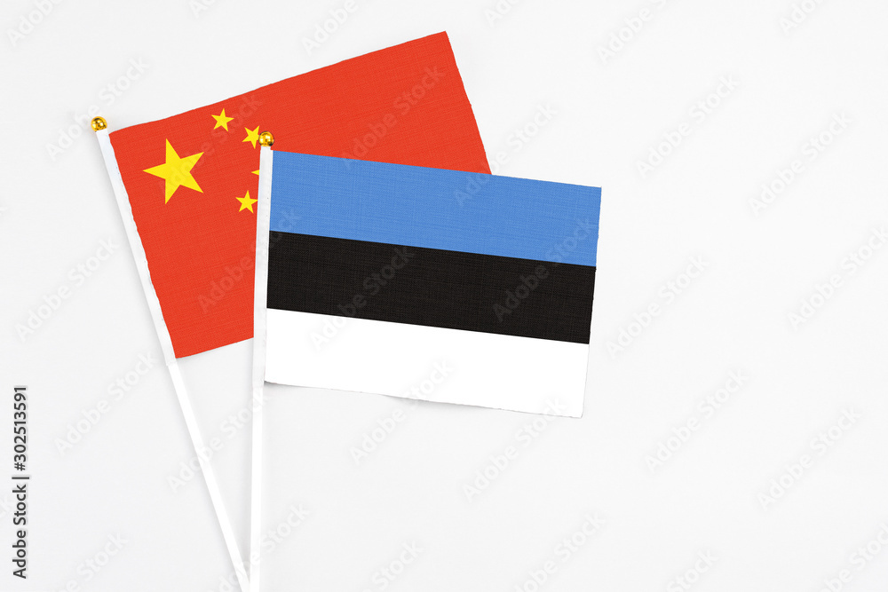 Estonia and China stick flags on white background. High quality fabric, miniature national flag. Peaceful global concept.White floor for copy space. Estonia and China stick flags on white background. High quality fabric, miniature national flag. Peaceful global concept.White floor for copy space.