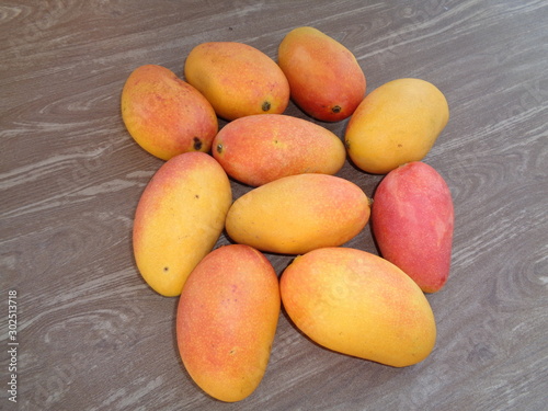 red mango, pelem podang suluh. podang mango ripe on the tree. indonesian exotic fruit with wooden brown background photo