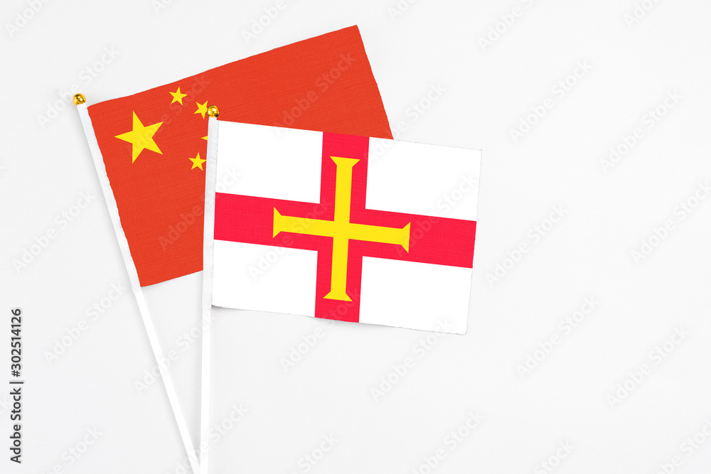 Guernsey and China stick flags on white background. High quality fabric, miniature national flag. Peaceful global concept.White floor for copy space.