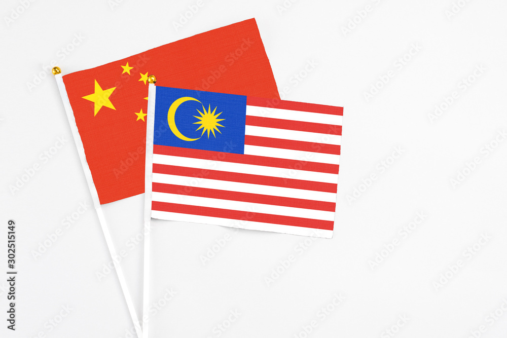 Malaysia and China stick flags on white background. High quality fabric, miniature national flag. Peaceful global concept.White floor for copy space. Malaysia and China stick flags on white background. High quality fabric, miniature national flag. Peaceful global concept.White floor for copy space.