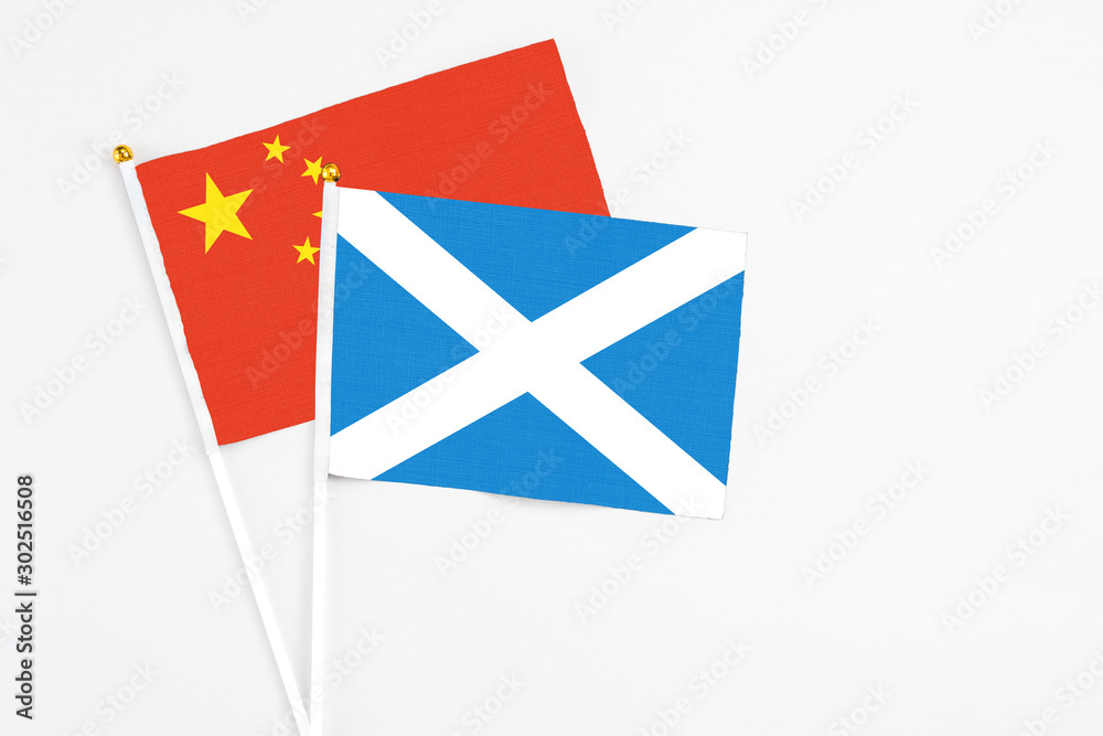 Scotland and China stick flags on white background. High quality fabric, miniature national flag. Peaceful global concept.White floor for copy space. Scotland and China stick flags on white background. High quality fabric, miniature national flag. Peaceful global concept.White floor for copy space.