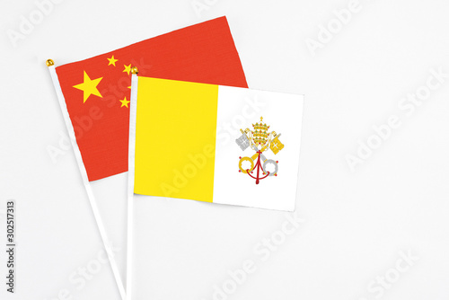 Vatican City and China stick flags on white background. High quality fabric, miniature national flag. Peaceful global concept.White floor for copy space.