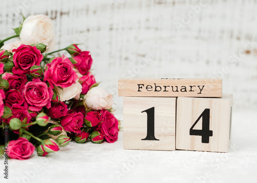 Bouquet of red roses and data 14 of February on wooden calendar on the white background. Happy Valentines Day, february 14 , copy space. Greeting card. Top view, flat lay. Love concept