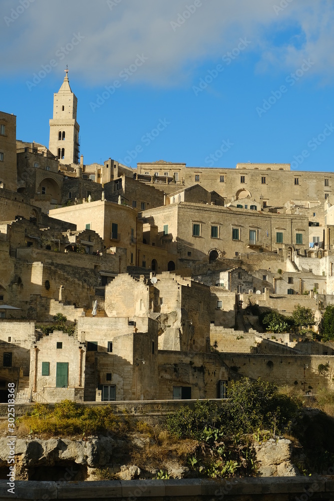 Panorama of the Sassi of Matera with houses in tuff stone. Church and bell tower at dawn with sky and clouds.