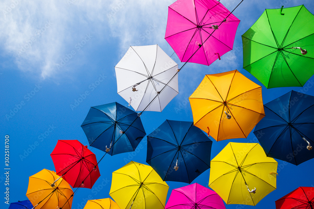 Beautiful group of colorful umbrellas hanging above the street against blue sky on a sunny day Beautiful group of colorful umbrellas hanging above the street against blue sky on a sunny day
