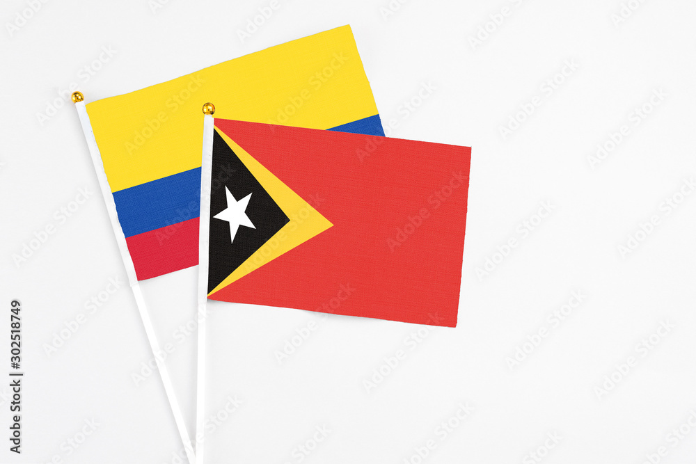 East Timor and Colombia stick flags on white background. High quality fabric, miniature national flag. Peaceful global concept.White floor for copy space. East Timor and Colombia stick flags on white background. High quality fabric, miniature national flag. Peaceful global concept.White floor for copy space.