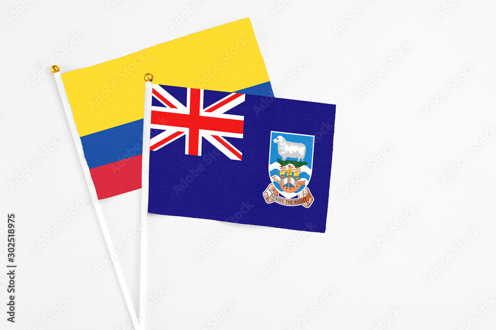 Fototapeta premium Falkland Islands and Colombia stick flags on white background. High quality fabric, miniature national flag. Peaceful global concept.White floor for copy space.