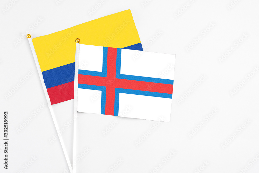 Faroe Islands and Colombia stick flags on white background. High quality fabric, miniature national flag. Peaceful global concept.White floor for copy space.