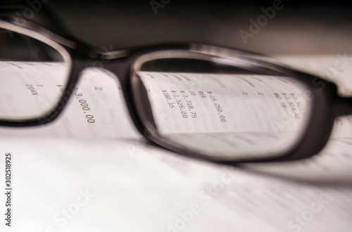 Figures from the financial report through the glass of glasses in a black frame