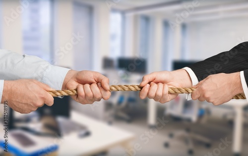 Business people pulling rope in opposite directions at office