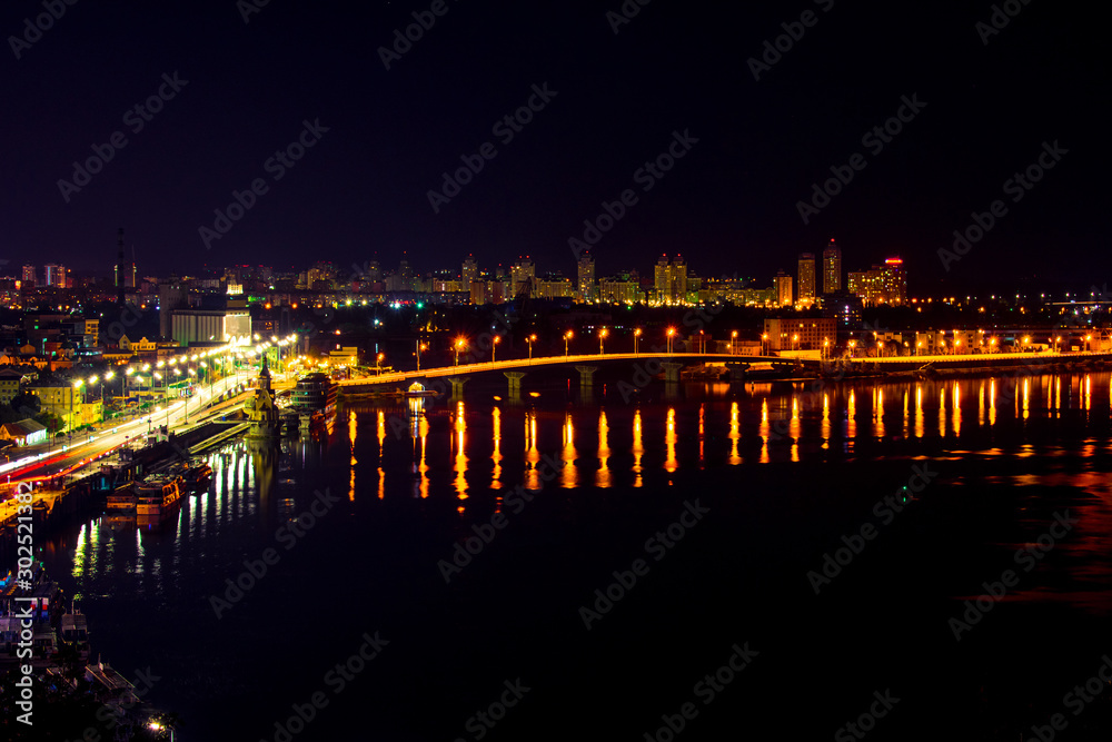 Night city landscape. Landscape of the city of Kiev in the night. A bridge across the river with bright colored lights. Night view of the capital of Ukraine