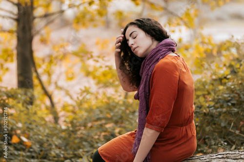 Young woman, dressed in casual clothes, with relaxed attitude, in a forest with autumn colors.