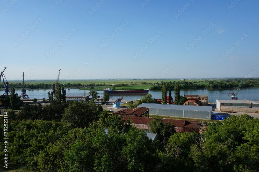 Warehouse facilities on the port territory. Port crane on the river Bank. Summer natural landscape. Warehouse facilities on the port territory. Port crane on the river Bank. Summer natural landscape.