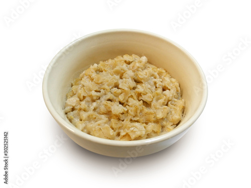 Oatmeal porridge in white earthenware bowl isolated on white background side view 