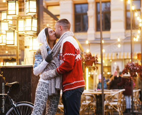 Lovely couple are kissing on the street while have a date on Christmas day.