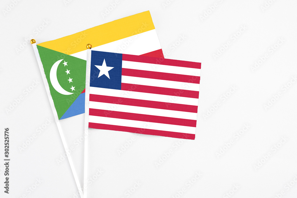 Liberia and Comoros stick flags on white background. High quality fabric, miniature national flag. Peaceful global concept.White floor for copy space.