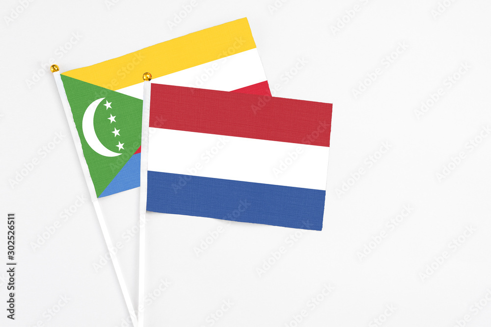 Netherlands and Comoros stick flags on white background. High quality fabric, miniature national flag. Peaceful global concept.White floor for copy space. Netherlands and Comoros stick flags on white background. High quality fabric, miniature national flag. Peaceful global concept.White floor for copy space.
