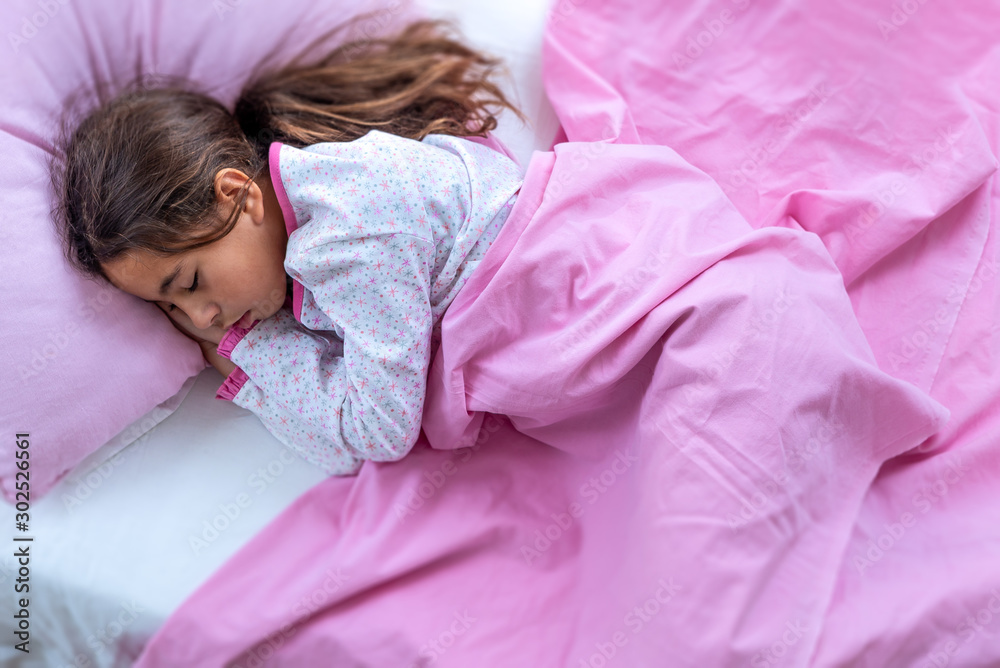 Sleeping beauty. Beautiful girl is weared a pajamas and pink enviroment  lying in bed. Close-up portrait of sleeping pre-teen girl. Child portrait  in pastel tones. Top view. Stock 写真 | Adobe Stock