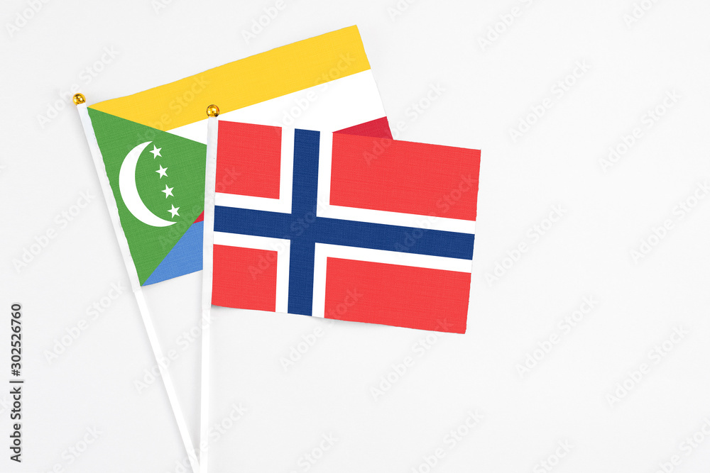 Norway and Comoros stick flags on white background. High quality fabric, miniature national flag. Peaceful global concept.White floor for copy space.