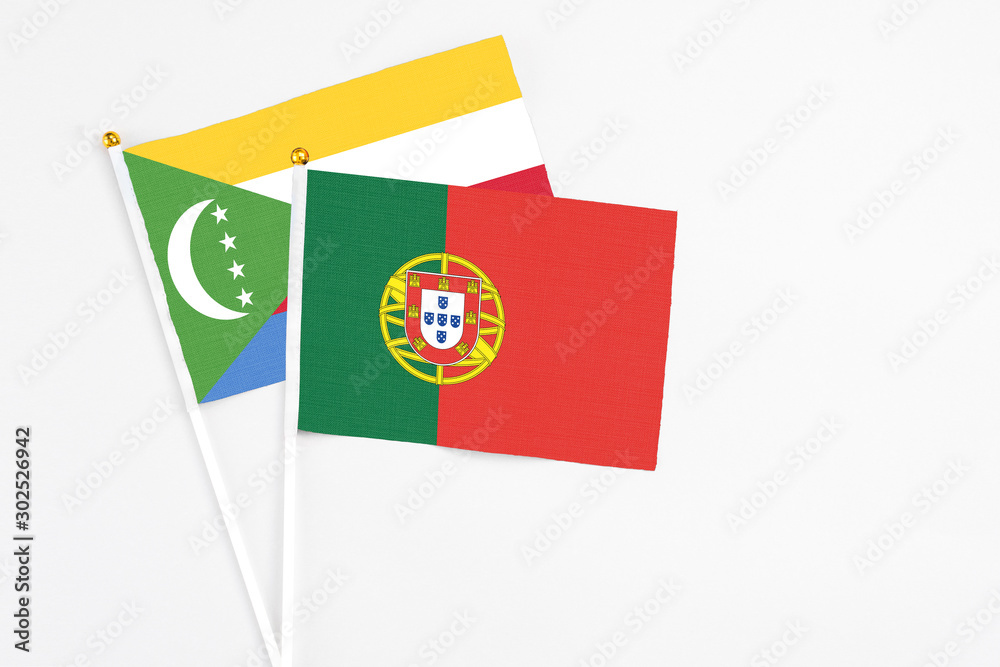 Portugal and Comoros stick flags on white background. High quality fabric, miniature national flag. Peaceful global concept.White floor for copy space. Portugal and Comoros stick flags on white background. High quality fabric, miniature national flag. Peaceful global concept.White floor for copy space.