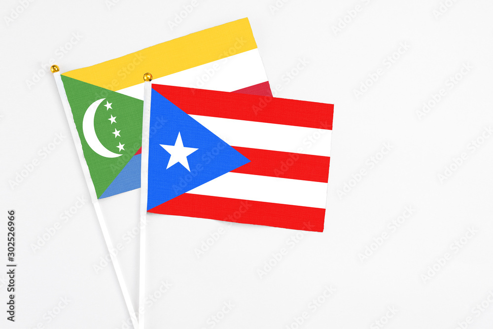 Puerto Rico and Comoros stick flags on white background. High quality fabric, miniature national flag. Peaceful global concept.White floor for copy space.