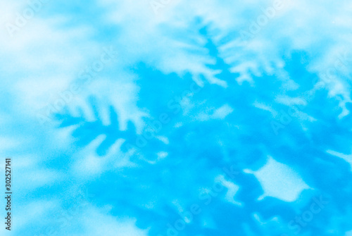 Winter background of abstract snowflake shadows on a bright blue background 