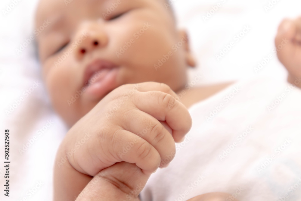 Newborn baby holding father's finger While sleeping comfortably on the white mattress During bedtime, the child's brain will work. To enhance Memory-boosting and learning-building skills Newborn baby holding father's finger While sleeping comfortably on the white mattress During bedtime, the child's brain will work. To enhance Memory-boosting and learning-building skills