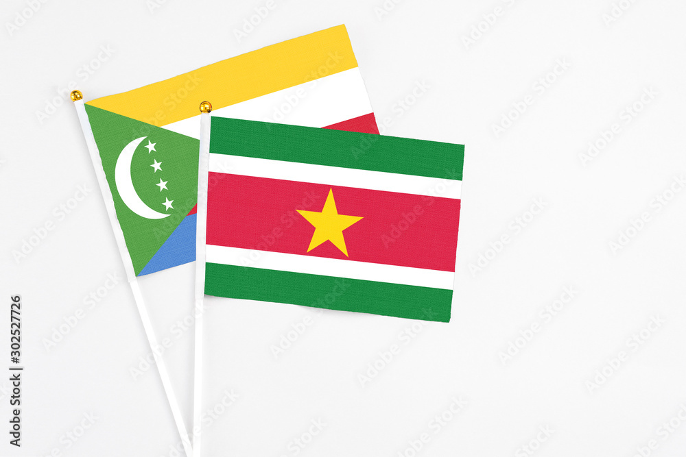 Suriname and Comoros stick flags on white background. High quality fabric, miniature national flag. Peaceful global concept.White floor for copy space. Suriname and Comoros stick flags on white background. High quality fabric, miniature national flag. Peaceful global concept.White floor for copy space.