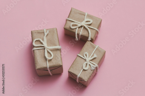 Set of parcels wrapping in brown craft paper and tie hemp string. Package. Delivery service. Online shopping. Your purchase. Gift box on a table. Pink solid background. © exienator