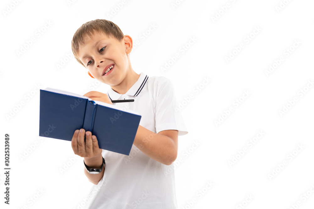 Portrait of a little caucasian boy writting something in notebook and smiles Portrait of a little caucasian boy writting something in notebook and smiles