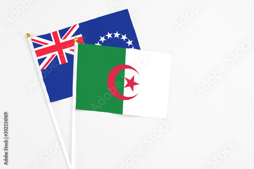 Algeria and Cook Islands stick flags on white background. High quality fabric, miniature national flag. Peaceful global concept.White floor for copy space.