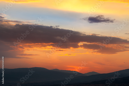 Amazing light on the cloud formations beautifully colored by sunset light and silhouettes of distant horizon mountains © Nikola