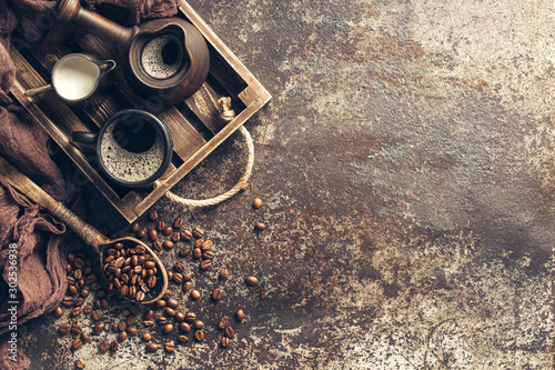 Coffee on wooden tray with coffee beans on dark textured background. Top view with copy space. Background with free text space.