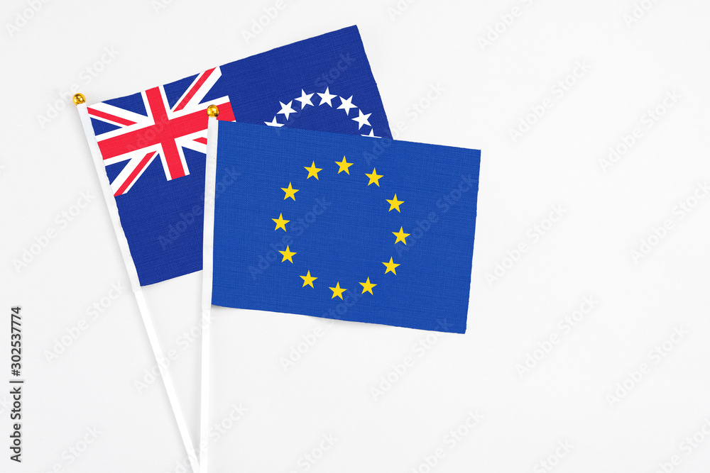 European Union and Cook Islands stick flags on white background. High quality fabric, miniature national flag. Peaceful global concept.White floor for copy space. European Union and Cook Islands stick flags on white background. High quality fabric, miniature national flag. Peaceful global concept.White floor for copy space.