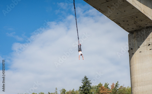 Man jumping from bridge bungee jumping.