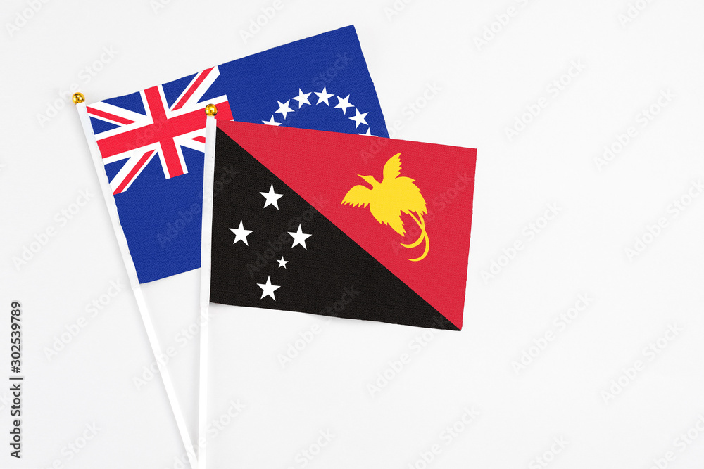 Papua New Guinea and Cook Islands stick flags on white background. High quality fabric, miniature national flag. Peaceful global concept.White floor for copy space. Papua New Guinea and Cook Islands stick flags on white background. High quality fabric, miniature national flag. Peaceful global concept.White floor for copy space.