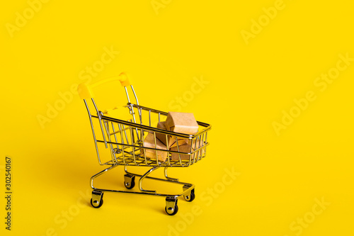 Small decorative trolley with boxes isolated on yellow background. High resolution. Shop sales, black friday concept