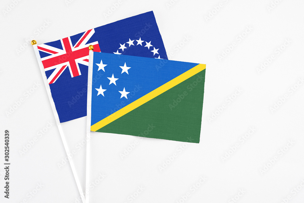 Solomon Islands and Cook Islands stick flags on white background. High quality fabric, miniature national flag. Peaceful global concept.White floor for copy space. Solomon Islands and Cook Islands stick flags on white background. High quality fabric, miniature national flag. Peaceful global concept.White floor for copy space.