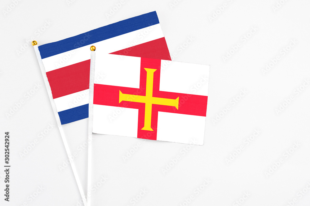 Guernsey and Costa Rica stick flags on white background. High quality fabric, miniature national flag. Peaceful global concept.White floor for copy space.