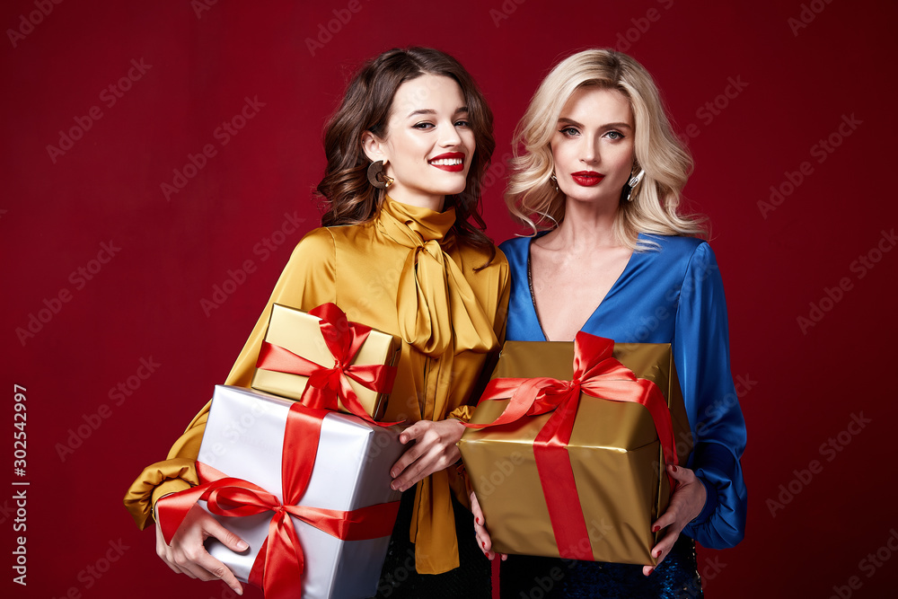 Two beautiful sexy young woman bright evening make-up red lips long fluffy eyelashes hold gift box holiday New Year joy fun happy merry Christmas Eve party celebration St. Valentine's Day girlfriend. Two beautiful sexy young woman bright evening make-up red lips long fluffy eyelashes hold gift box holiday New Year joy fun happy merry Christmas Eve party celebration St. Valentine's Day girlfriend.