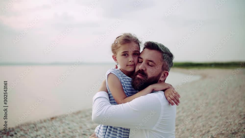 Mature father with small daughter on a holiday standing by the lake, hugging. Mature father with small daughter on a holiday standing by the lake, hugging.