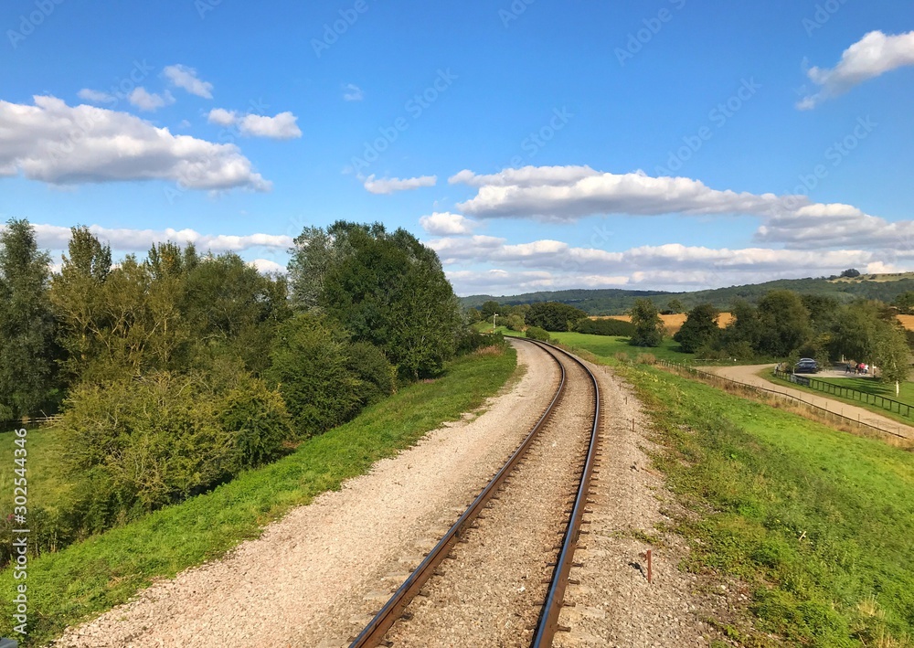 Single railway track through countryside on a bright, sunny day