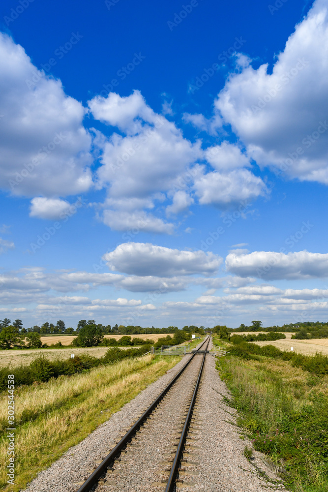 Single railway track through countryside on a bright, sunny day