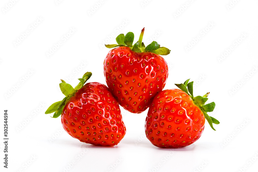 Close up of three ripe strawberries balancing on each other. All are isloated against a plain white background with space for copy Close up of three ripe strawberries balancing on each other. All are isloated against a plain white background with space for copy