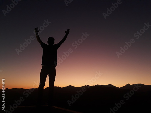 standing with arms wide open at sunset