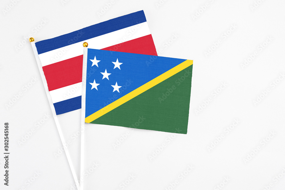 Solomon Islands and Costa Rica stick flags on white background. High quality fabric, miniature national flag. Peaceful global concept.White floor for copy space. Solomon Islands and Costa Rica stick flags on white background. High quality fabric, miniature national flag. Peaceful global concept.White floor for copy space.