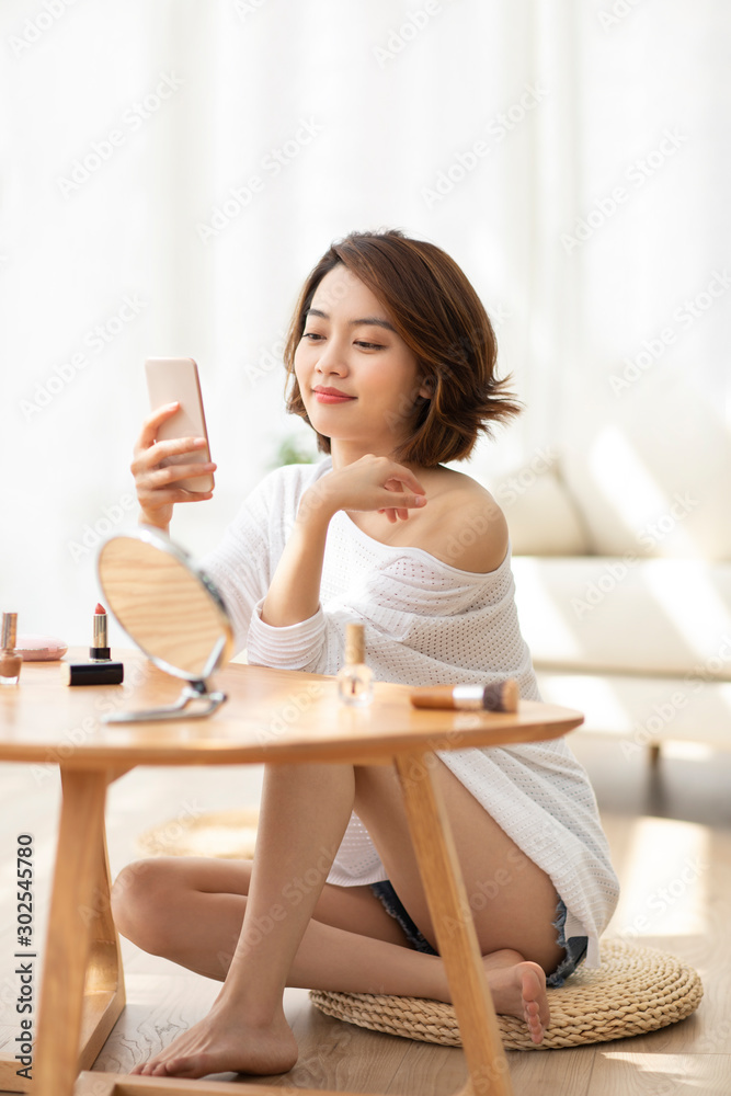 Young Chinese woman using smartphone at home Young Chinese woman using smartphone at home